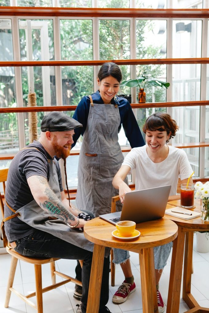 cafe business owners looking at laptop with team member looking happy